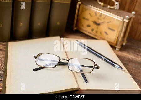 Open book with eyeglasses and a pen for notes. Open books ready for reading on the desk Stock Photo