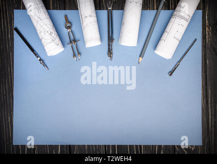 Compasses, rulers from the drawing and a pencil on a blue background. Architectural background with rolls of technical drawings and blueprints. Flat l Stock Photo