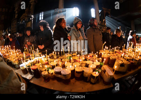 Blagoevgrad, Bulgaria - February 10, 2019: Worshippers light candles on jars with honey during a religious ritual marking the day of Saint Haralampi - Stock Photo