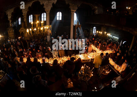 Blagoevgrad, Bulgaria - February 10, 2019: Worshippers light candles on jars with honey during a religious ritual marking the day of Saint Haralampi - Stock Photo