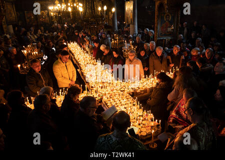 Blagoevgrad, Bulgaria - February 10, 2019: Worshippers light candles on jars with honey during a religious ritual marking the day of Saint Haralampi - Stock Photo