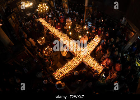 Blagoevgrad, Bulgaria - February 10, 2019: Worshippers light candles on jars with honey during a religious ritual marking the day of Saint Haralampi - Stock Photo