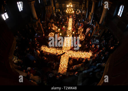 Blagoevgrad, Bulgaria - February 10, 2019: Worshippers light candles on jars with honey during a religious ritual marking the day of Saint Haralampi - Stock Photo