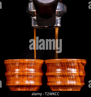 Coffees are being prepared in small wooden cups by a coffee machine. Stock Photo