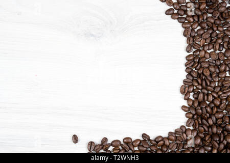 fresh coffee beans on a white wooden texture table, can be used as a background. With space next to it for text Stock Photo