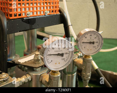 closeup of two analog indicators of temperature with arrows showing current hot or cold condition of liquid paint in automatic pneumatic air pressure  Stock Photo