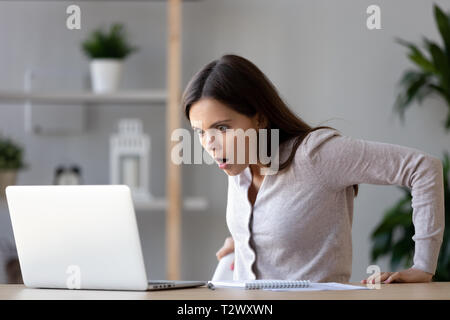 Shocked woman looking at laptop screen surprised with bad news Stock Photo