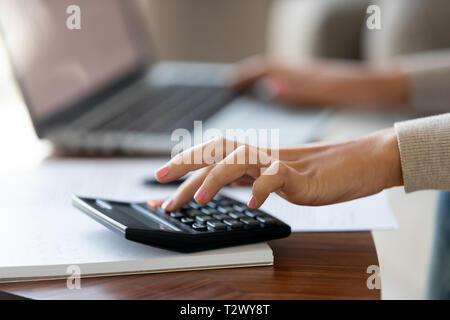 Cropped closeup image caucasian woman using calculator and computer Stock Photo