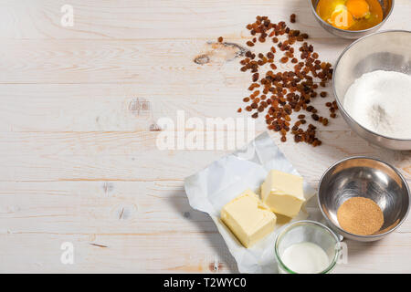 Ingredients for the Easter dough with text space. Eggs, flour, butter, raisins, dry yeast, sugar, milk, sour cream on white wooden background Stock Photo