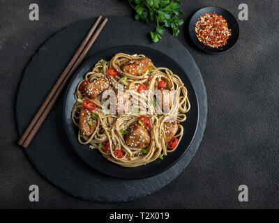 Chicken teriyaki with asian noodles udon , sesame, rustic stone background. Closeup. Chinese/Japanese noodles Stock Photo