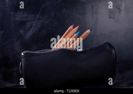 pencil case with wooden pencils and blackboard at school Stock Photo
