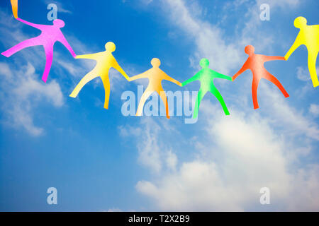 Multi coloured Paper Dolls holding hands Stock Photo