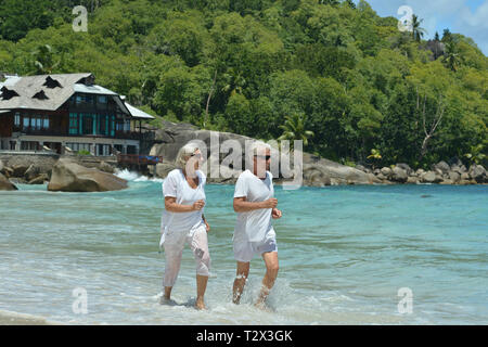 Happy elderly couple running  on sandy beach Stock Photo