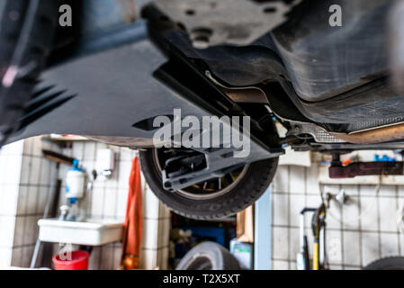 Car chassis on the lift, view from the bottom. Visible exhaust system, wheels, brake hoses. Stock Photo