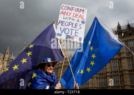 On the day that Prime Minister Theresa May meets with Labour leader Jeremy Corbyn in an attempt to break the Brexit deadlock in parliament, a pro-EU protestor holds a placard and an EU flag opposite Parliament in Westminster, on 3rd April 2019, in London, England. Stock Photo