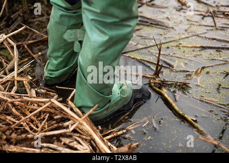 fisherman stands in the water in rubber waterproof boots for