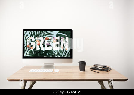 computer with green leaves and green lettering on monitor on wooden desk Stock Photo