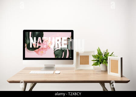 computer with green leaves and nature illustration on monitor on wooden desk Stock Photo