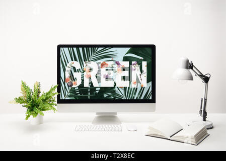 computer with green lettering and tropical leaves on monitor on desk on white background Stock Photo