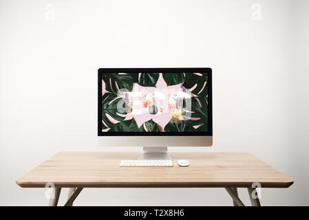 computer with green monstera leaves and eco lettering on monitor on wooden desk Stock Photo