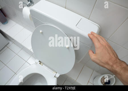 Close-up Of Man Finger Pressing On Button For Flushing Toilet Stock Photo