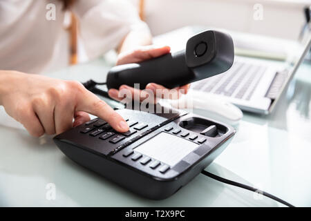 Close-up Of A Businesswoman's Hand Dialing Telephone Number To Make Phone Call In Office Stock Photo