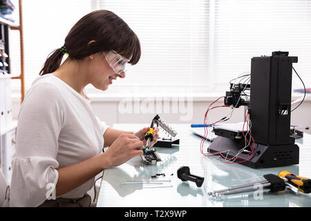 Female Engineer Or Tech Repairs Electronic Device In Hardware Repair Shop Stock Photo
