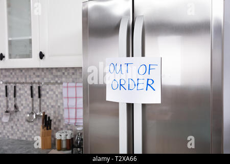 Written Text Out Of Order Message On Paper Over The Stuck Closed Refrigerator In Kitchen Stock Photo