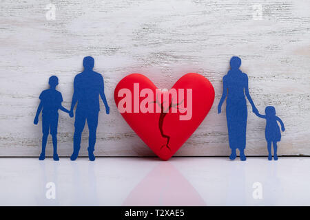 Broken Heart Between Cutout Blue Family Against White Textured Background Stock Photo