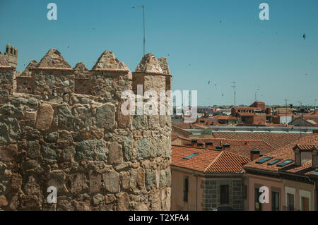 Battlement with merlons and crenels over stone tower and rooftops on buildings at Avila. With an imposing wall around the gothic city center in Spain. Stock Photo