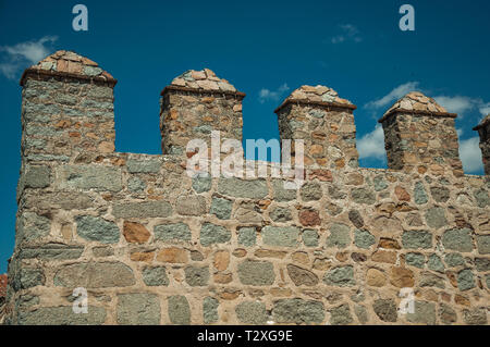Battlement with merlons and crenels over rough stone wall encircling the town of Avila. With an imposing wall around the gothic city center in Spain. Stock Photo