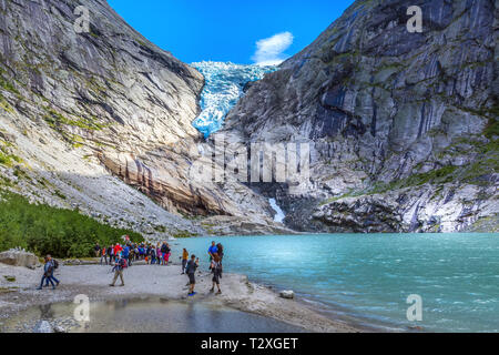 Norway, Olden - August 1, 2018: People at near lake and Briksdal or Briksdalsbreen glacier with melting blue ice, nature landmark Stock Photo