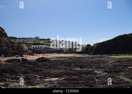 Hope Cove Fishing Village beyond Holiday Makers on the Sandy Beach. South Hams, Devon, UK. Stock Photo