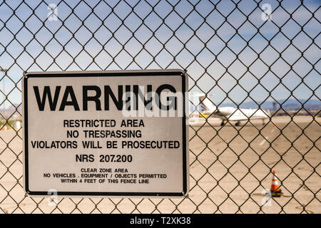 LAS VEGAS, NEVADA, USA - FEBRUARY 2019: Warning sign on a fence around McCarran International Airport. In the background is a private executive jet. Stock Photo