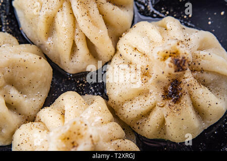 Georgian dumplings Khinkali with meat and red papper, on black plate Stock Photo