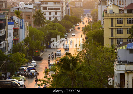 Daily traffic and city life on the busy streets of Mandalay during sunset. Stock Photo