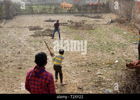 Three little Indian rural boys are playing cricket on farmer's land Stock Photo