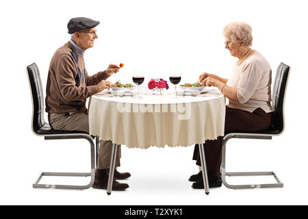 Senior couple eating a salad at a restaurant table isolated on white background Stock Photo