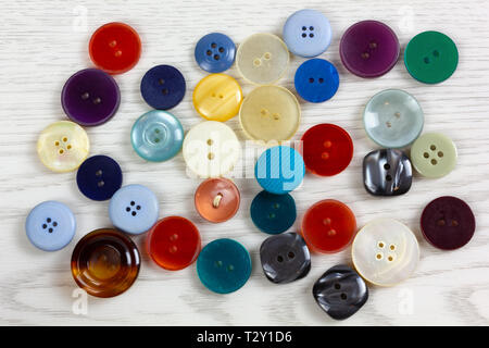 Button of different shapes and colors on a white wooden table Stock Photo
