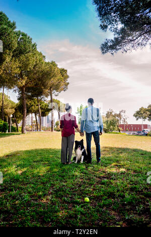Young couple posing with a dog in a city park Stock Photo