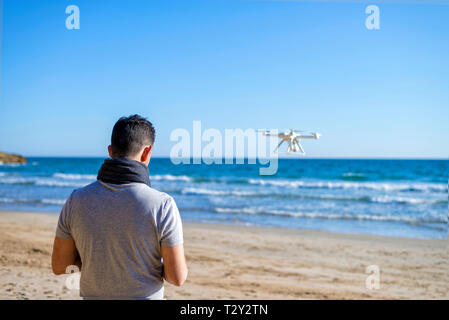Rear view of a Man on a beach testing its drone and recording v Stock Photo