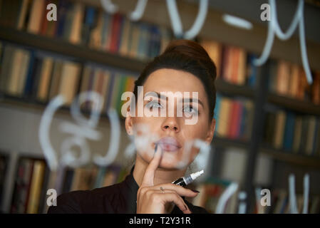 Educated business woman writing down math formula on glass Stock Photo