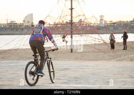 Young man riding a bike in Poblenou Beach Stock Photo