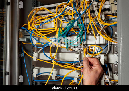 Networks engineer connecting cables to a network switch in a communications server cabinet Stock Photo