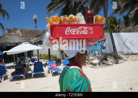 Beach vendor selling mango and pineapple in a Coca Cola box on top of his head Stock Photo