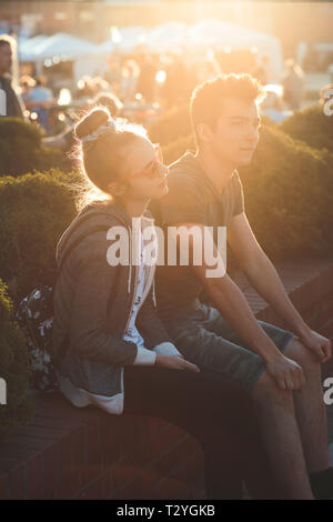 Couple of friends, teenage girl and boy,  having fun together, sitting in center of town, spending time together Stock Photo