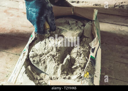Cement powder in the cement bag, a hand hold the trowel scoop cement powder cray for construction work. Stock Photo