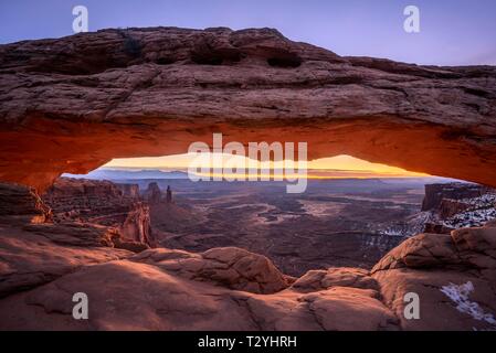 View through arch Mesa Arch at sunrise, Colorado River Canyon with the La Sal Mountains behind, view at Grand View Point Trail, Island in the Sky Stock Photo