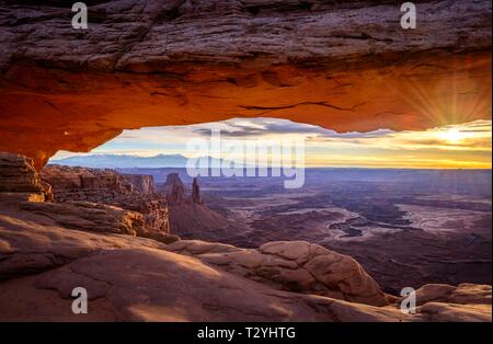 View through arch Mesa Arch at sunrise, Colorado River Canyon with the La Sal Mountains behind, view at Grand View Point Trail, Island in the Sky