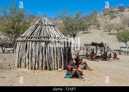 Himba women in a village with wooden huts, Kaokoland, Namibia Stock Photo